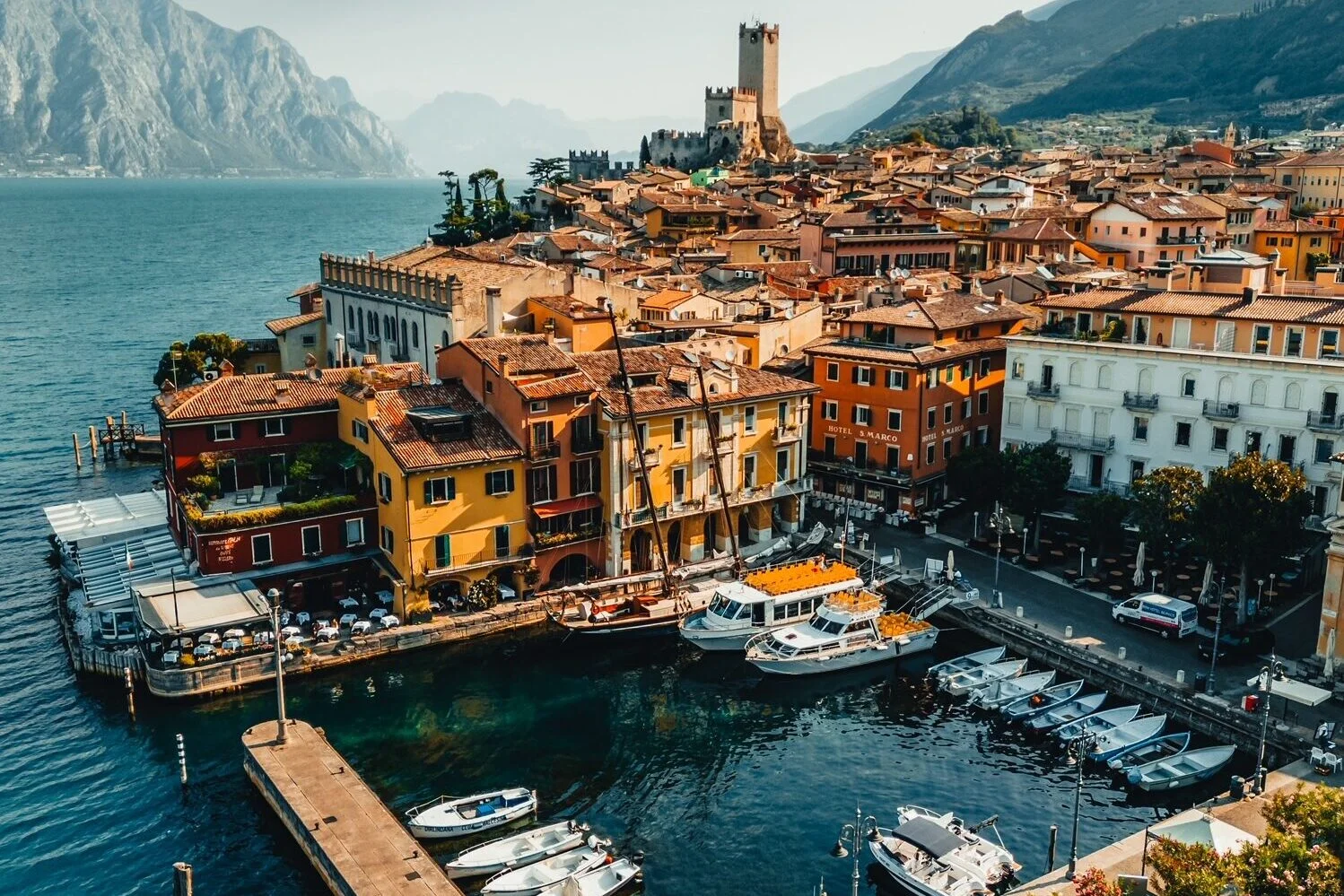 Eine Weitwinkelansicht von Malcesine in Italien, die den Hafen und die umliegenden Häuser zeigt.