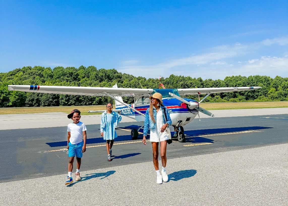 A group of people standing in front of an airplane

Description automatically generated