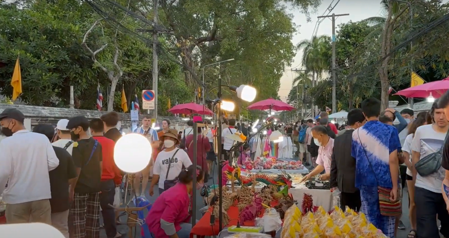 A street market with people and umbrellas

Description automatically generated