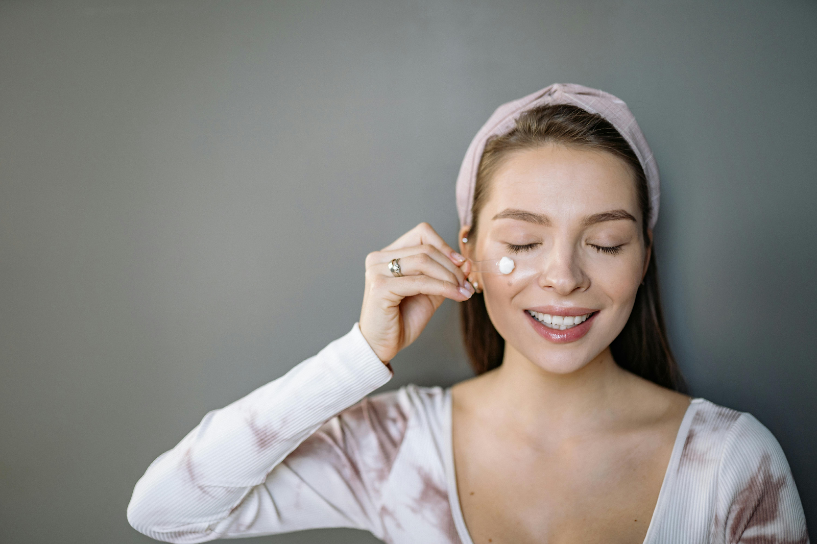 A woman applying moisturizer to her face.