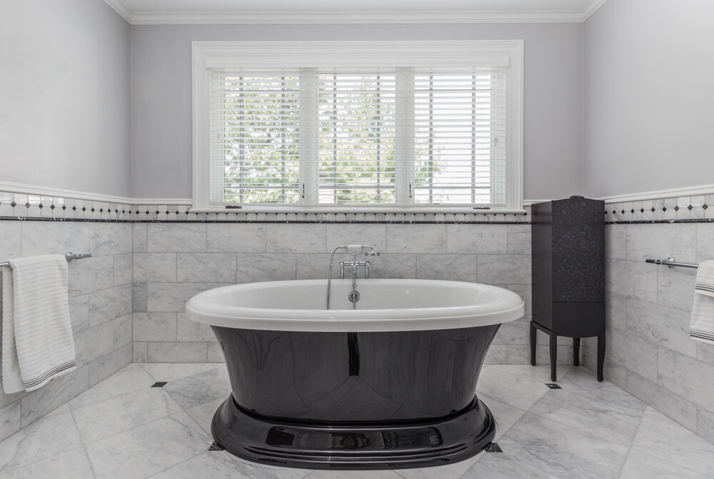 Classic bathroom with a black freestanding bathtub and marble floors.