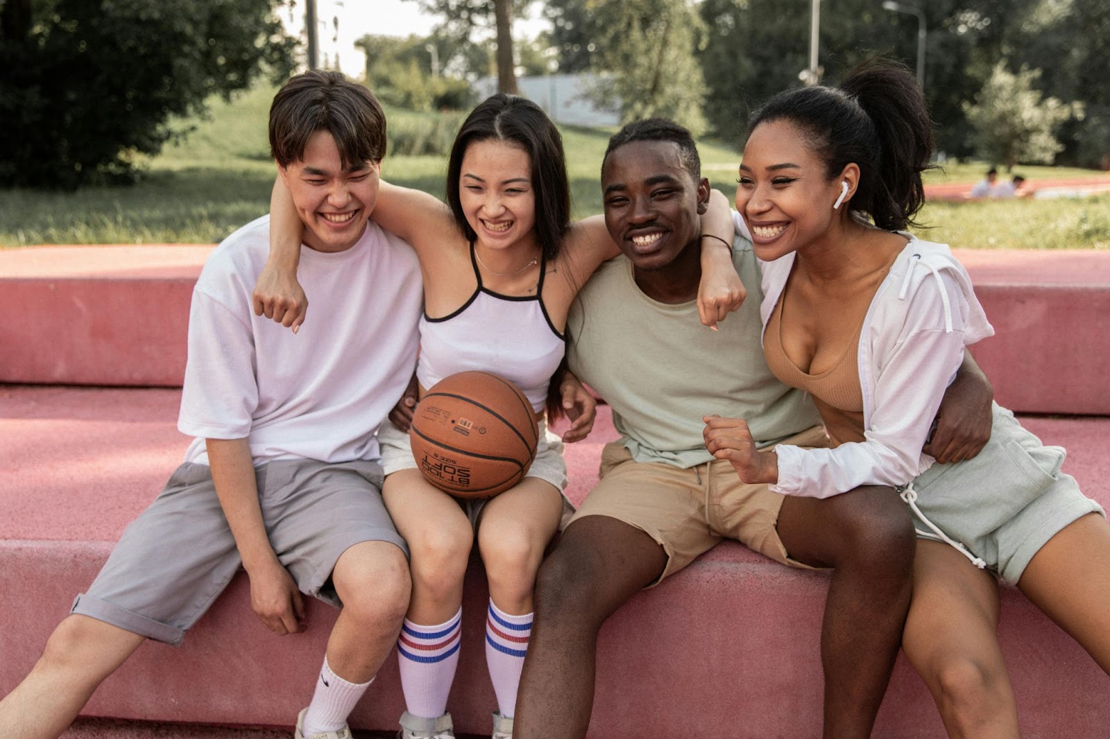 A group of four friends hanging out at the park with a basketball