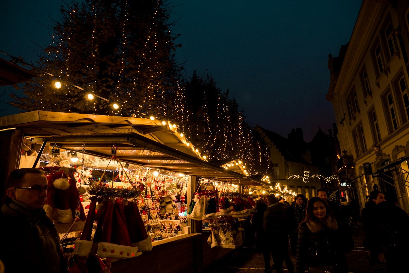 People standing near market stalls in a lit street