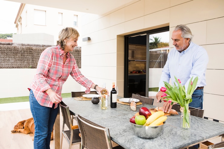 Table en céramique utilisée en extérieur par un couple, soulignant les avantages de ce matériau pour une utilisation en terrasse et les inconvénients à anticiper pour bien choisir.