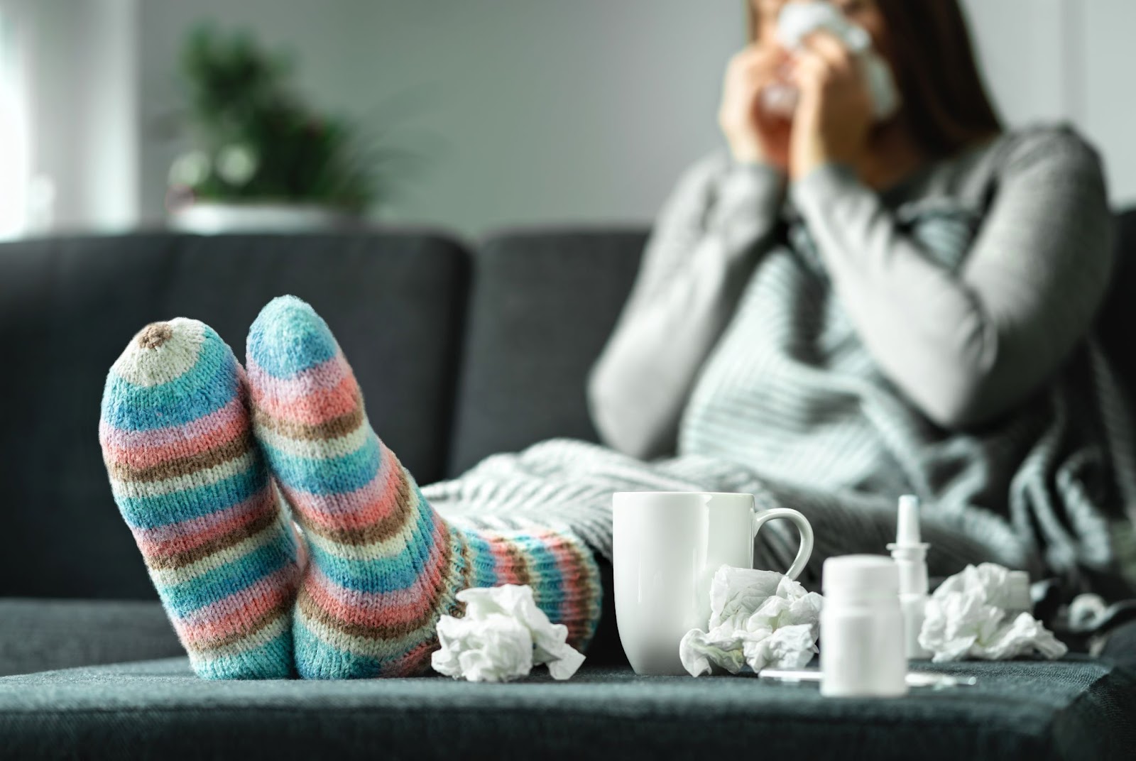 A person blowing their nose on a couch.