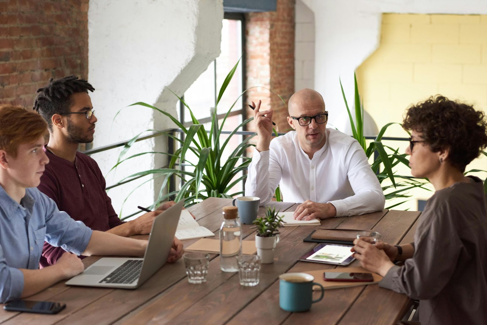 An IP manager speaks with office workers seated at a table.