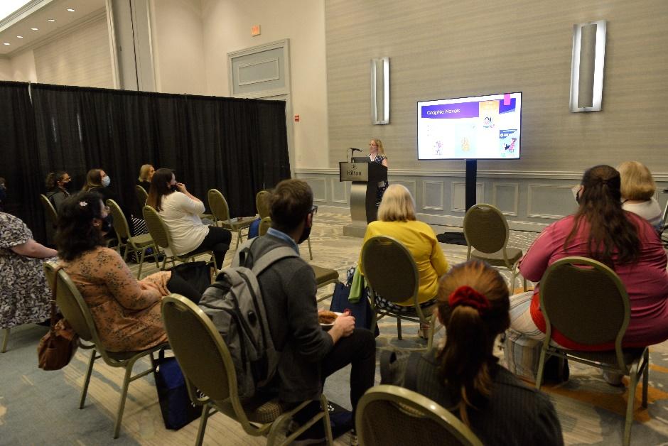 A group of people sitting in chairs watching a presentation

Description automatically generated with medium confidence