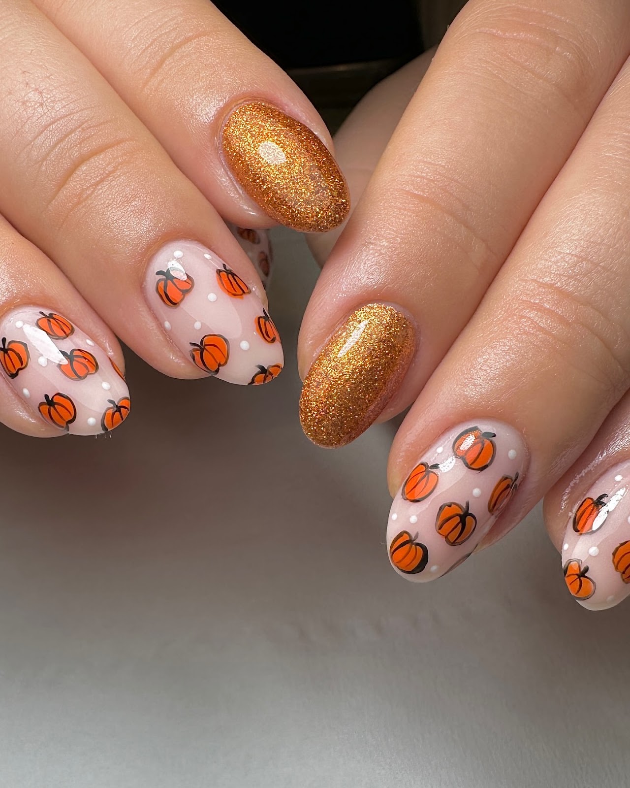 Close-up of hands with fall nail design having Pumpkin Designs