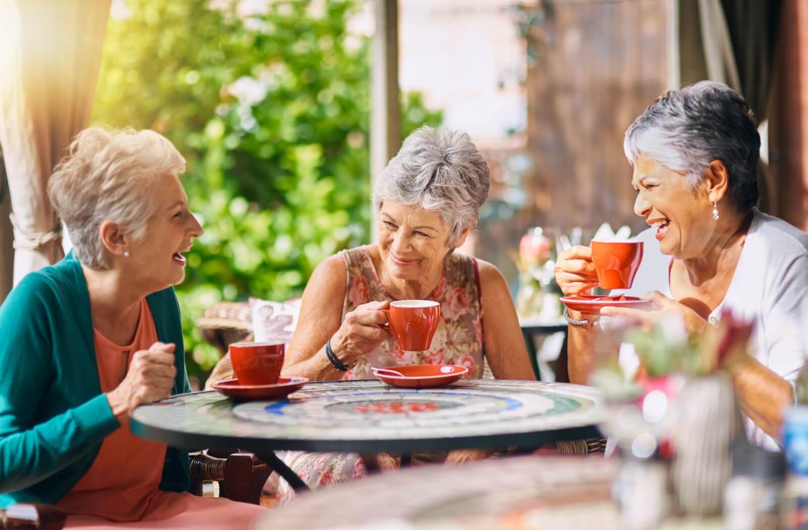 Three happy seniors laughing and drinking tea together.