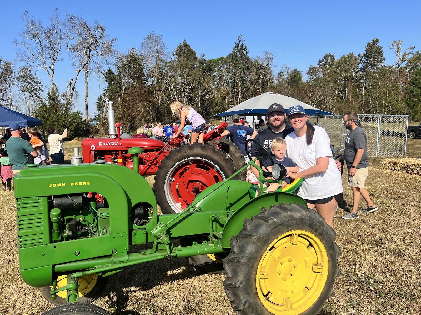 three people pose with a tractor