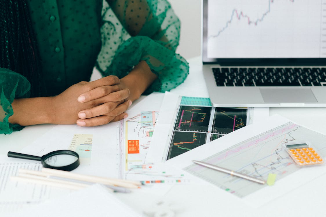 A person analyzes financial charts and graphs at a desk, indicating business trading activity. Stock Photo