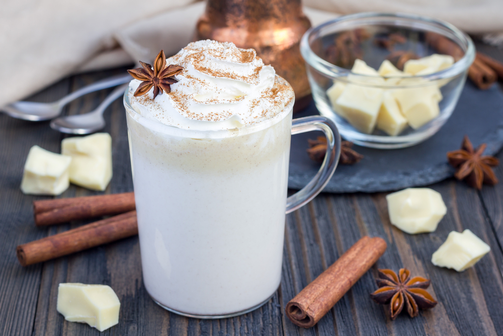 White hot chocolate decorated with whipped cream, cinnamon, and anise