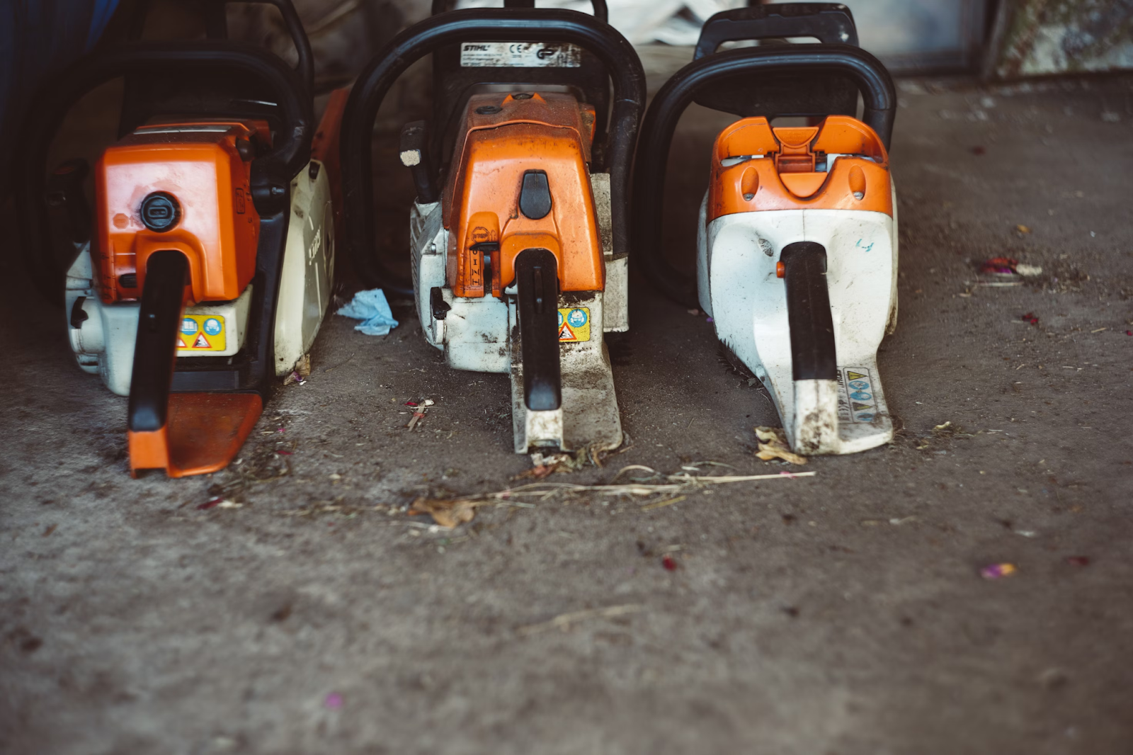 This image depicts three chainsaws set on the ground. 