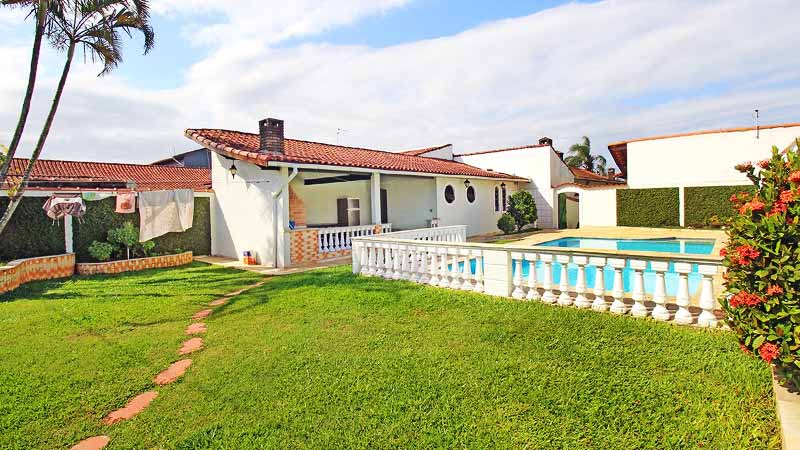 Edícula em uma casa com piscina e um grande gramado, com flores e plantas