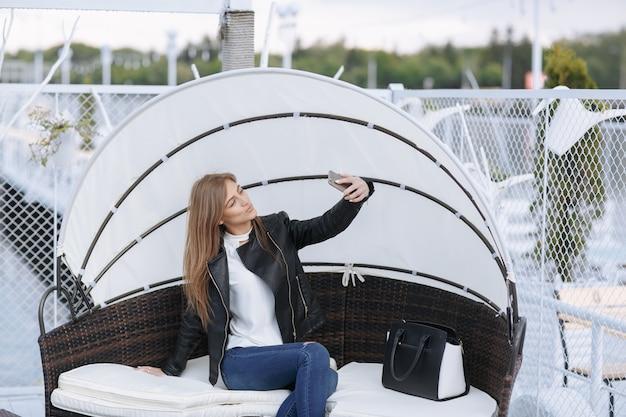 Woman sitting in a wicker armchair with umbrella making an auto photo