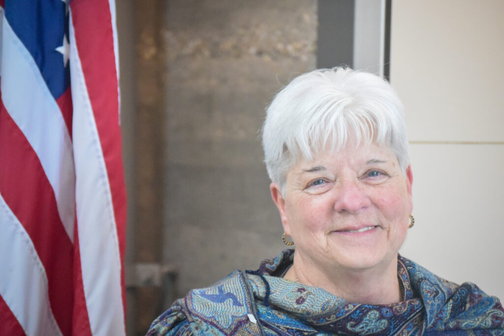 Woman stands next to an American flag