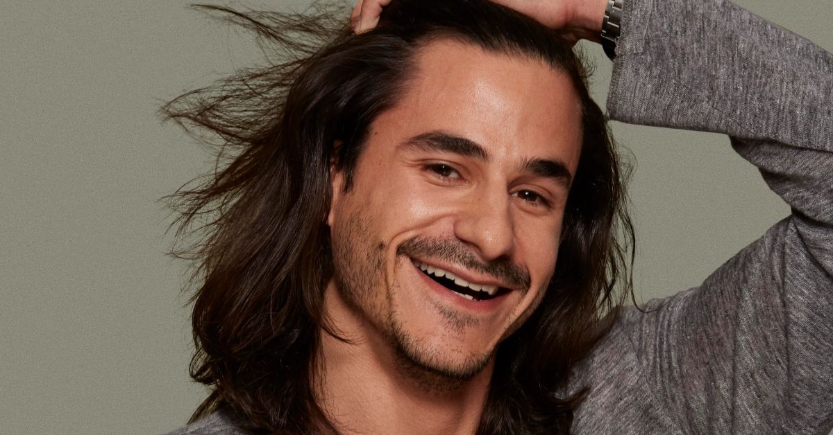 A smiling man with long hair, embodying the essence of the "Man-Bob" style, radiates warmth and positivity.