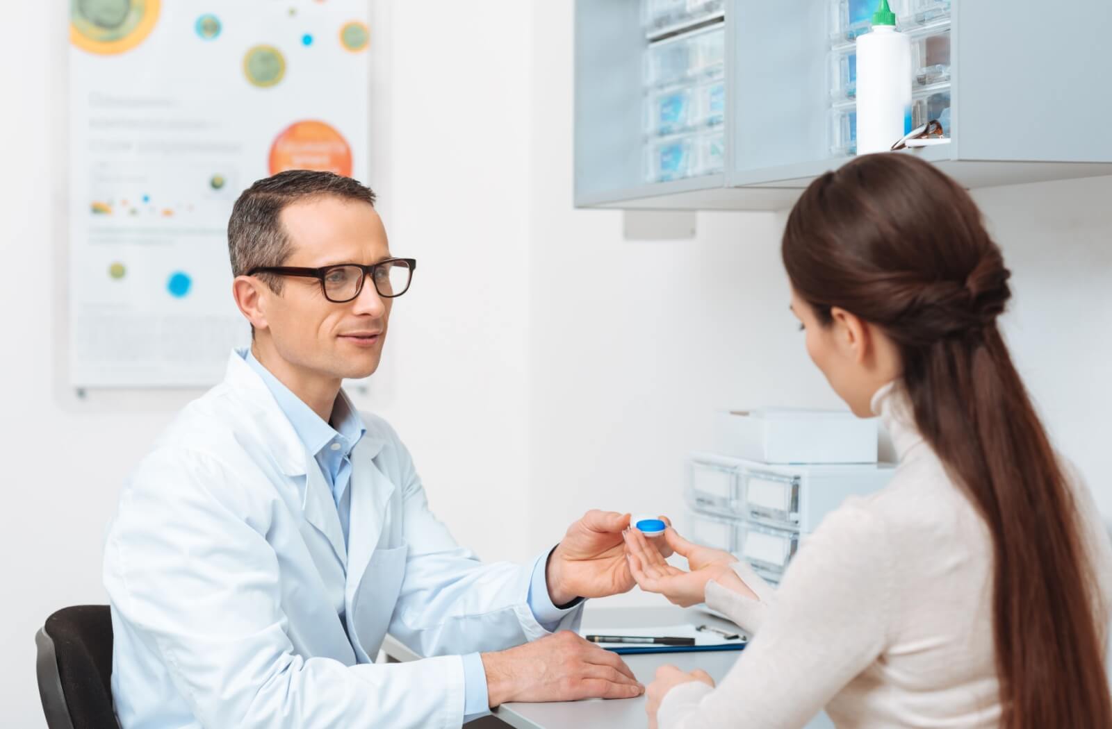 An optometrist explains proper contact lens maintenance to their patient during their annual contact lens fitting.