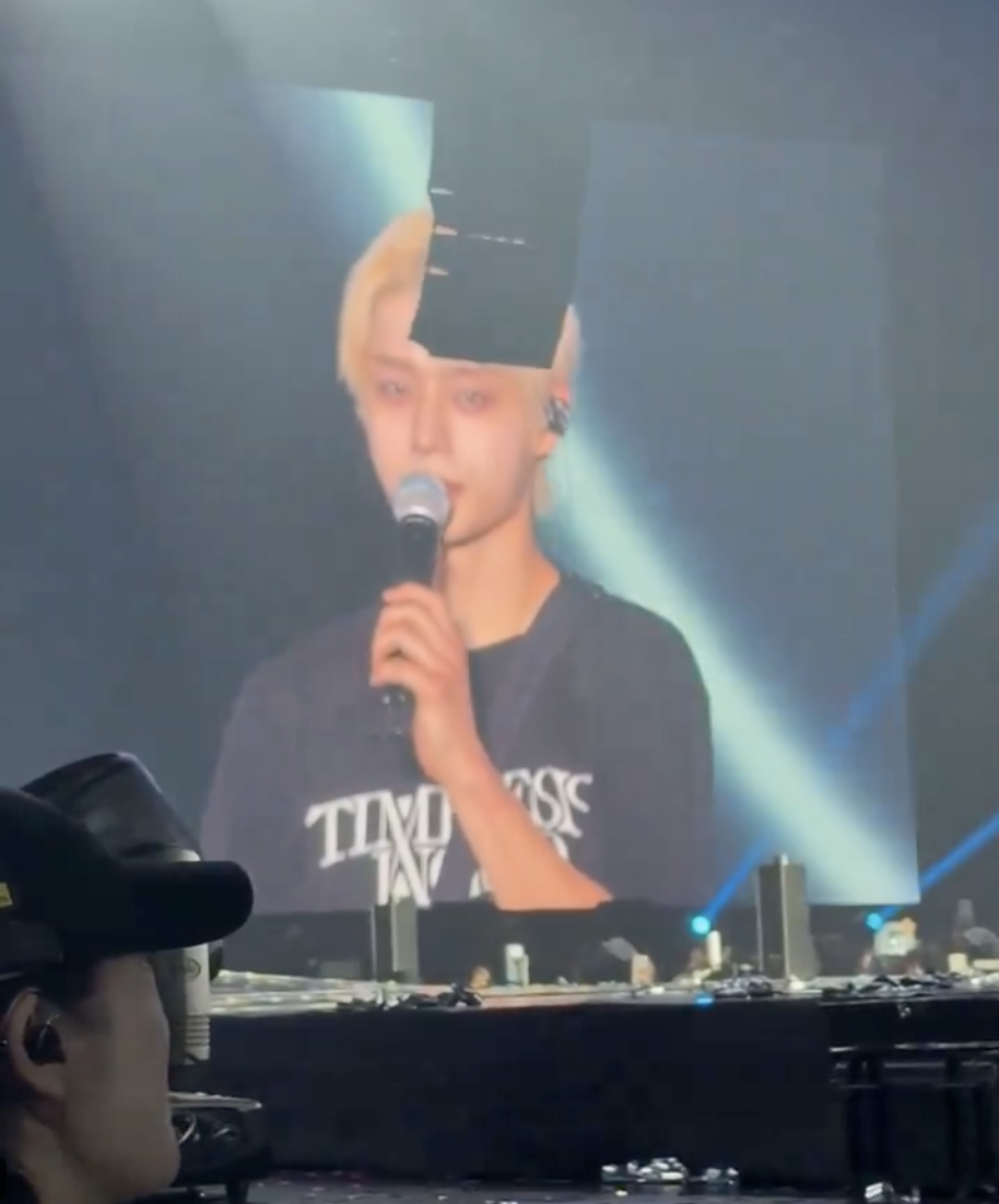  ZEROBASEONE Kim Jiwoong on a screen with mic on his hand and he is wearing a black polo