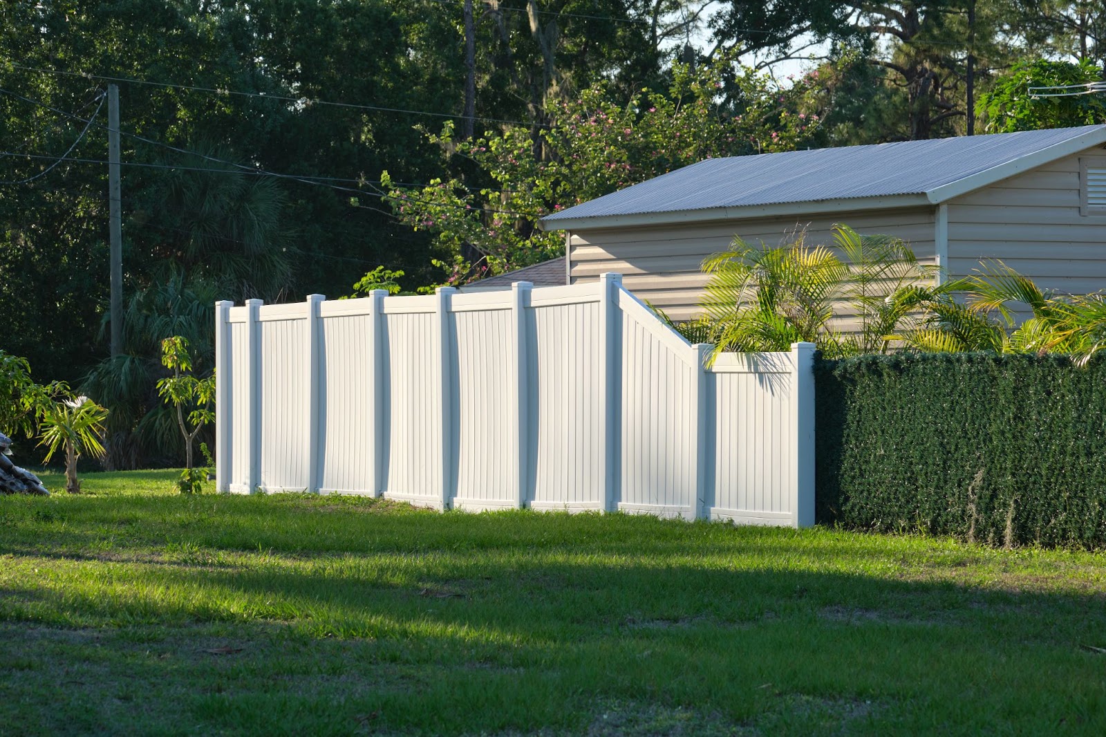 Vinyl fence on grass with a house in the background. 