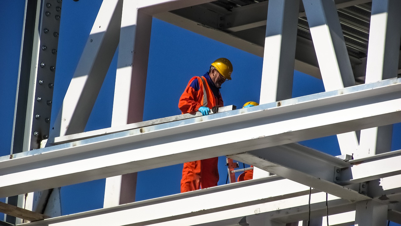 A construction worker in a building project inspects a steel girder for a commercial building. 