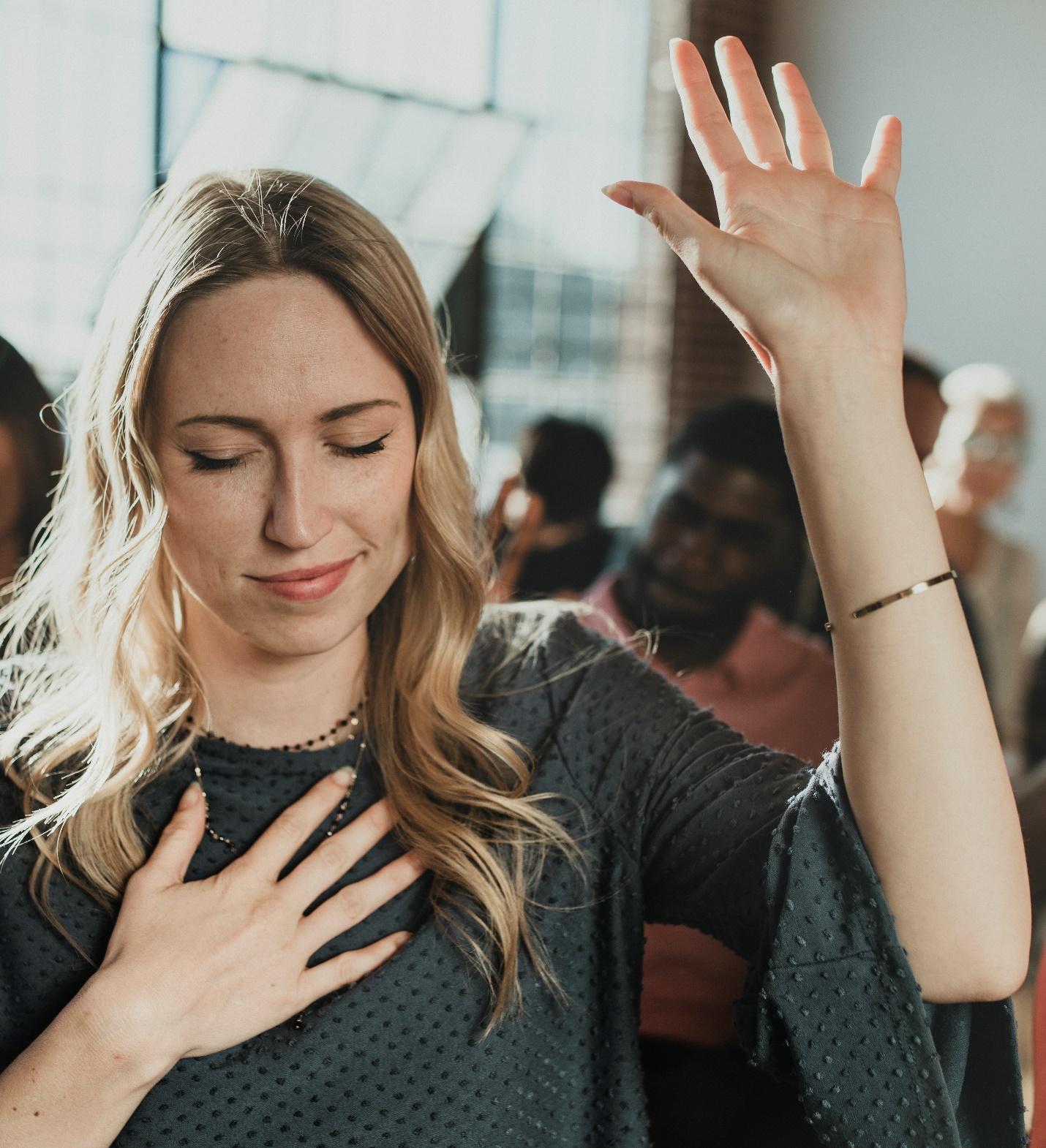 A person with her hand up and her heart

Description automatically generated