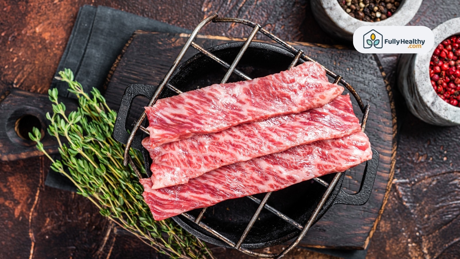 Raw Wagyu beef slices on grill with herbs and pepper
