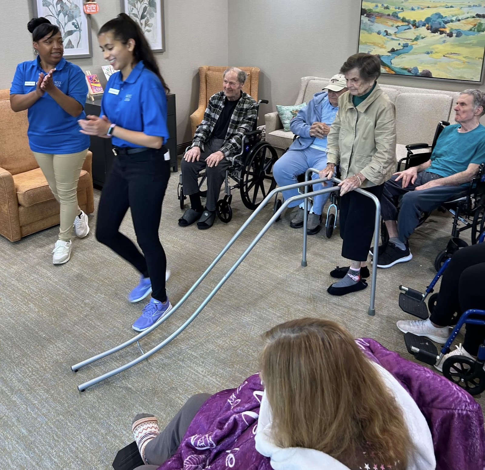 Assisted living staff helping a senior women with an assisted bowling ball apparatus