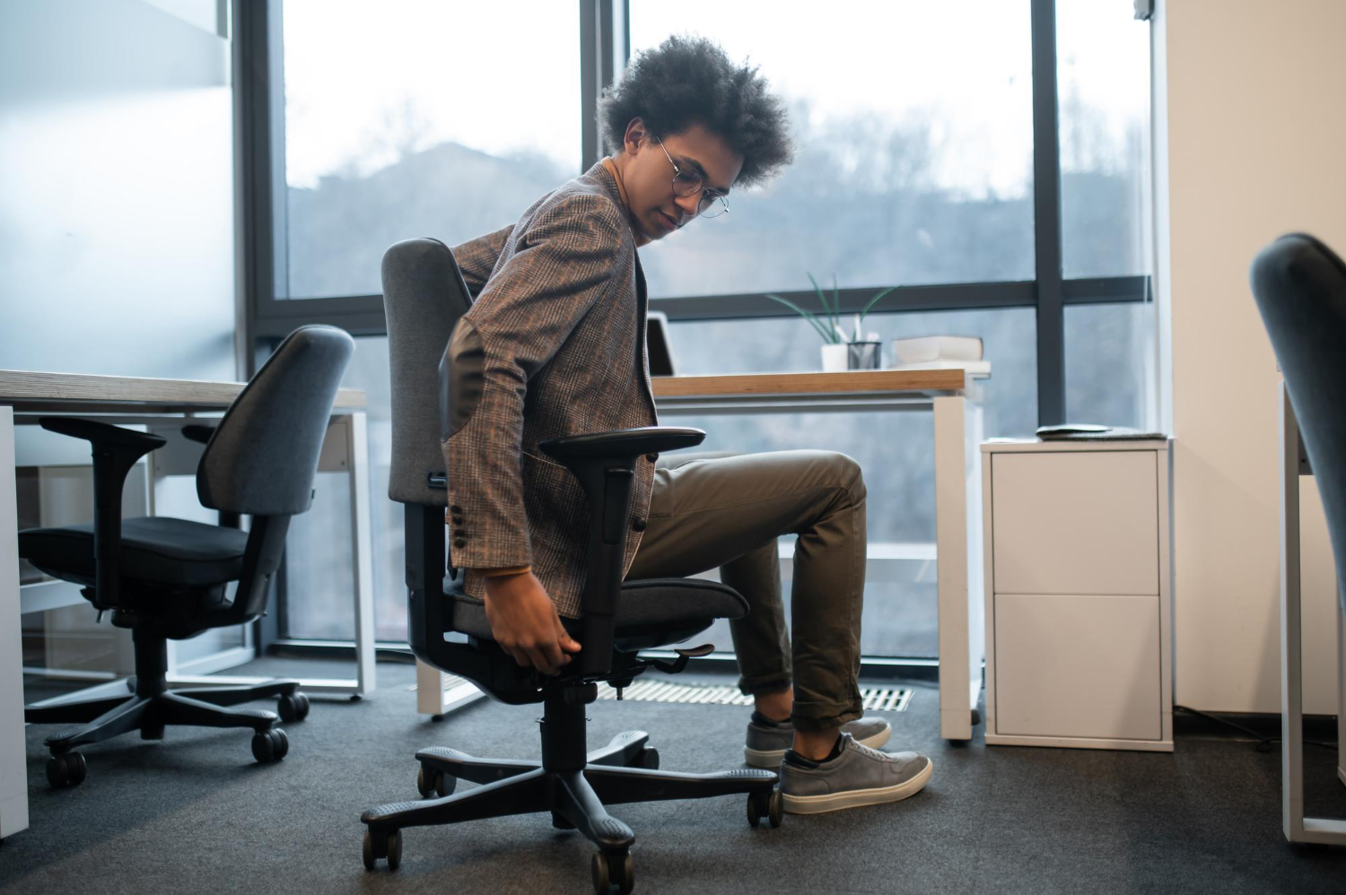 An office worker adjusts his new hybrid home office setup, showing that ergonomic needs change over time.