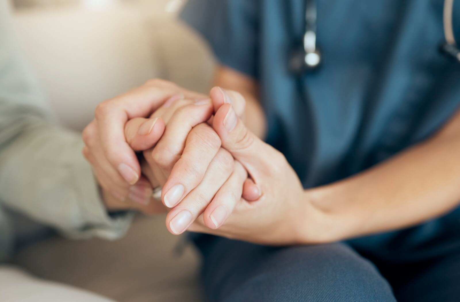 Close-up of a caregiver holding an assisted living resident's hand.