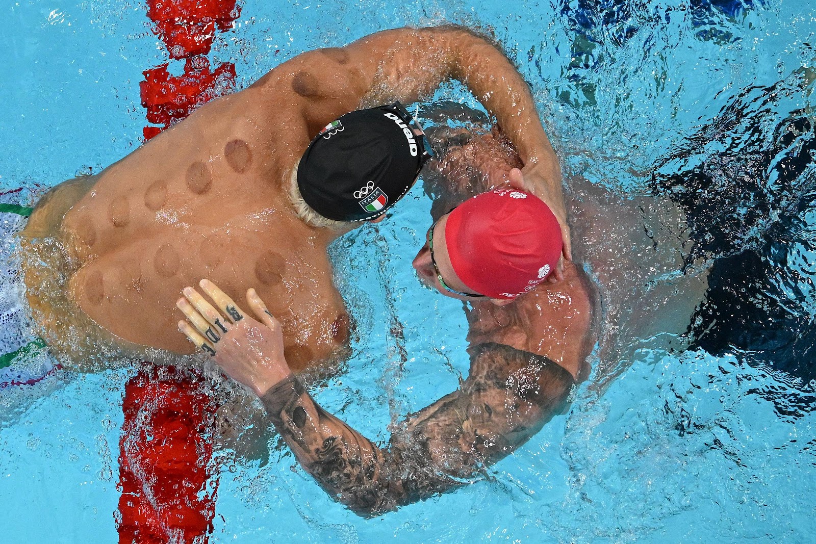 Italian swimmer Nicolo Martinenghi hugs British swimmer Adam Peaty after winning the Men's 100m Breaststroke Final at the Paris 2024 Olympic Games on July 28, 2024