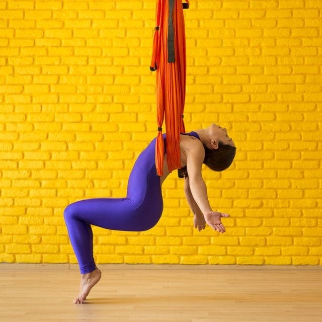 womna handing on a swing performing aerial yoga