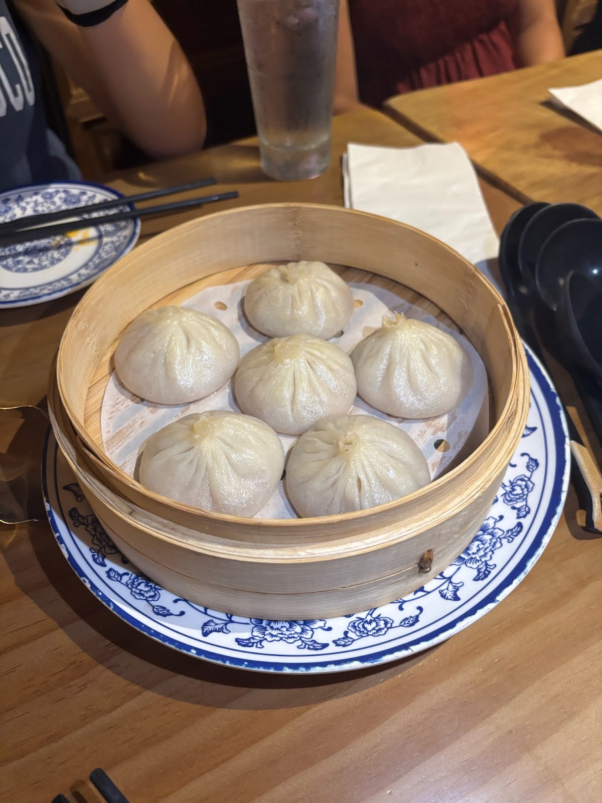 Chicken dumplings served in a wooden basket atop a blue & white plate. 