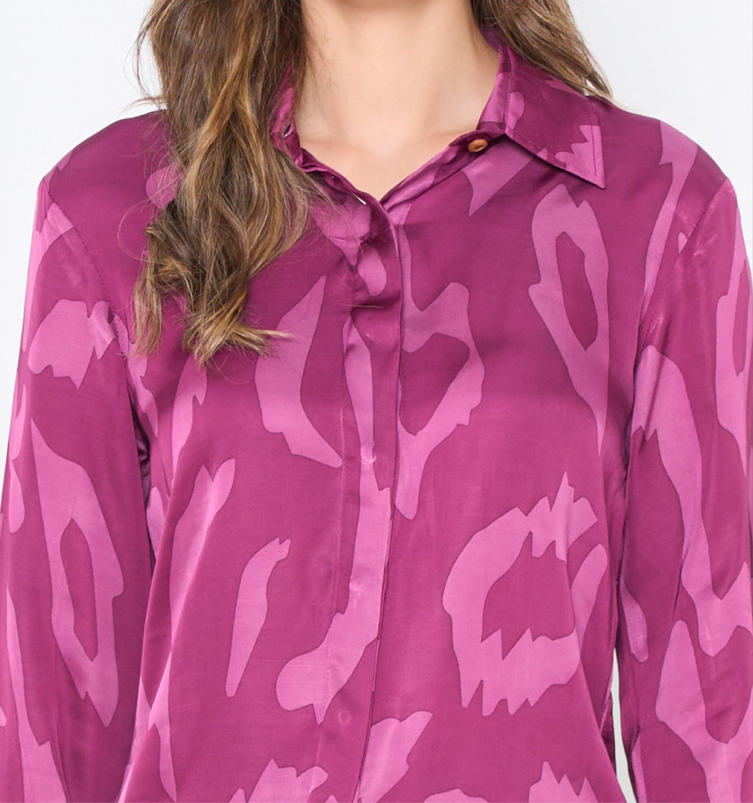 A closeup image showing long sleeved women's batik shirt in plum rimba from batik boutique, standing in a office