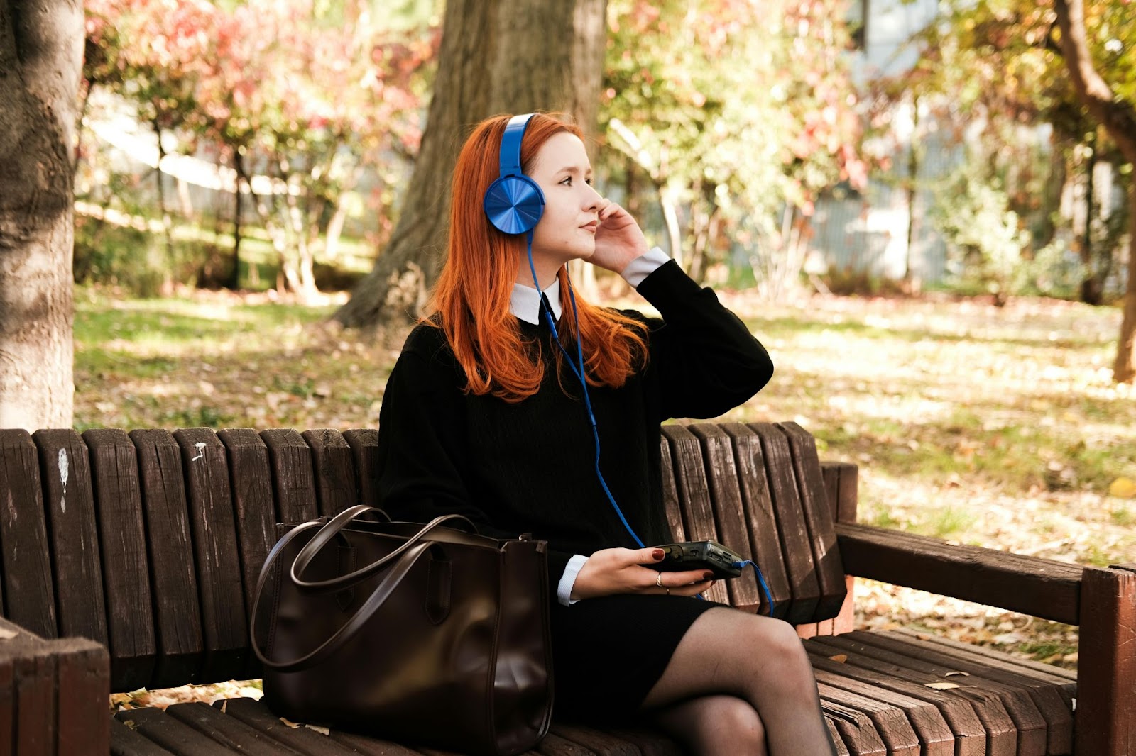 A female college students with headphones sitting on a bench