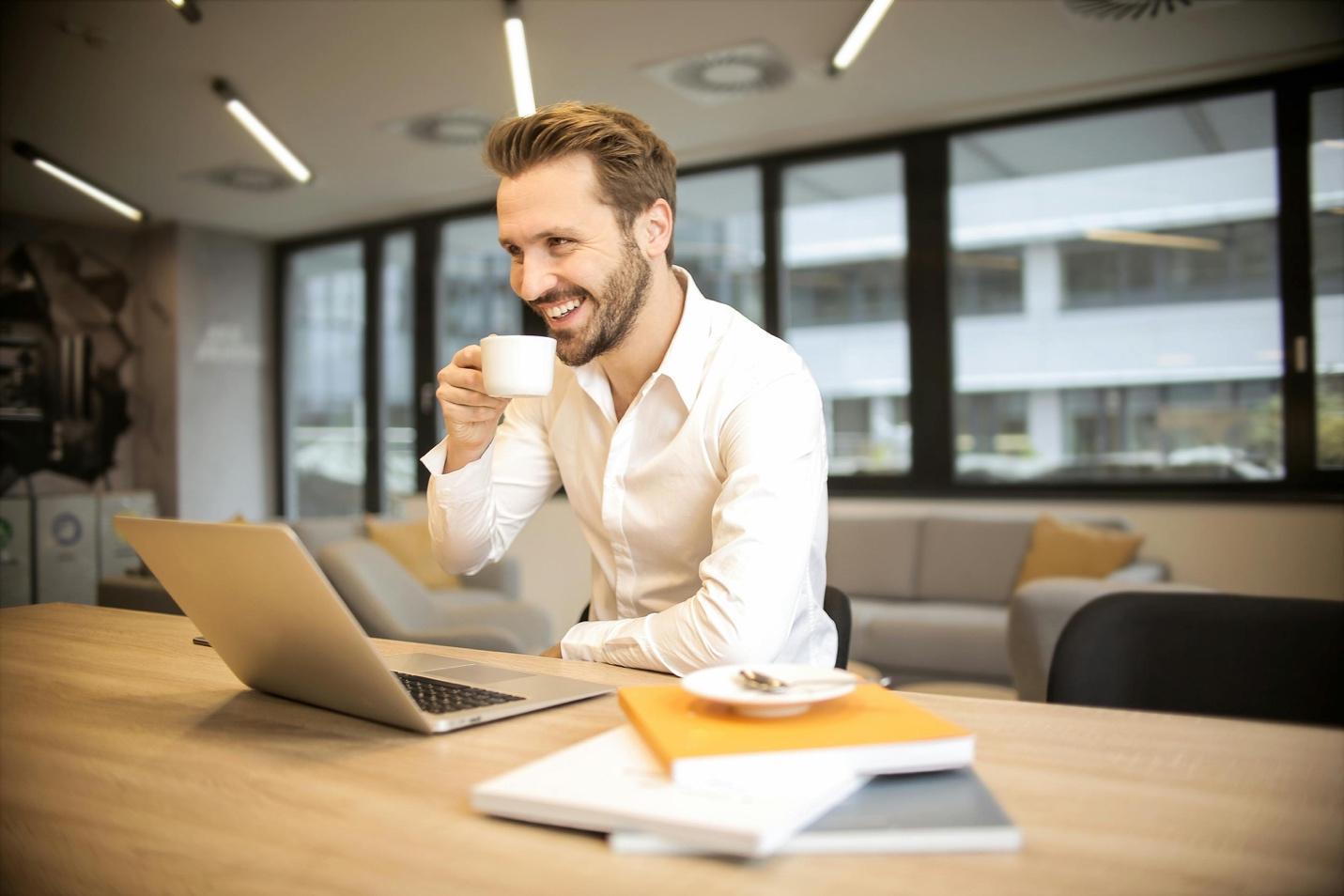 A person sitting at a table with a computer and a cup of coffee  AI-generated content may be incorrect.