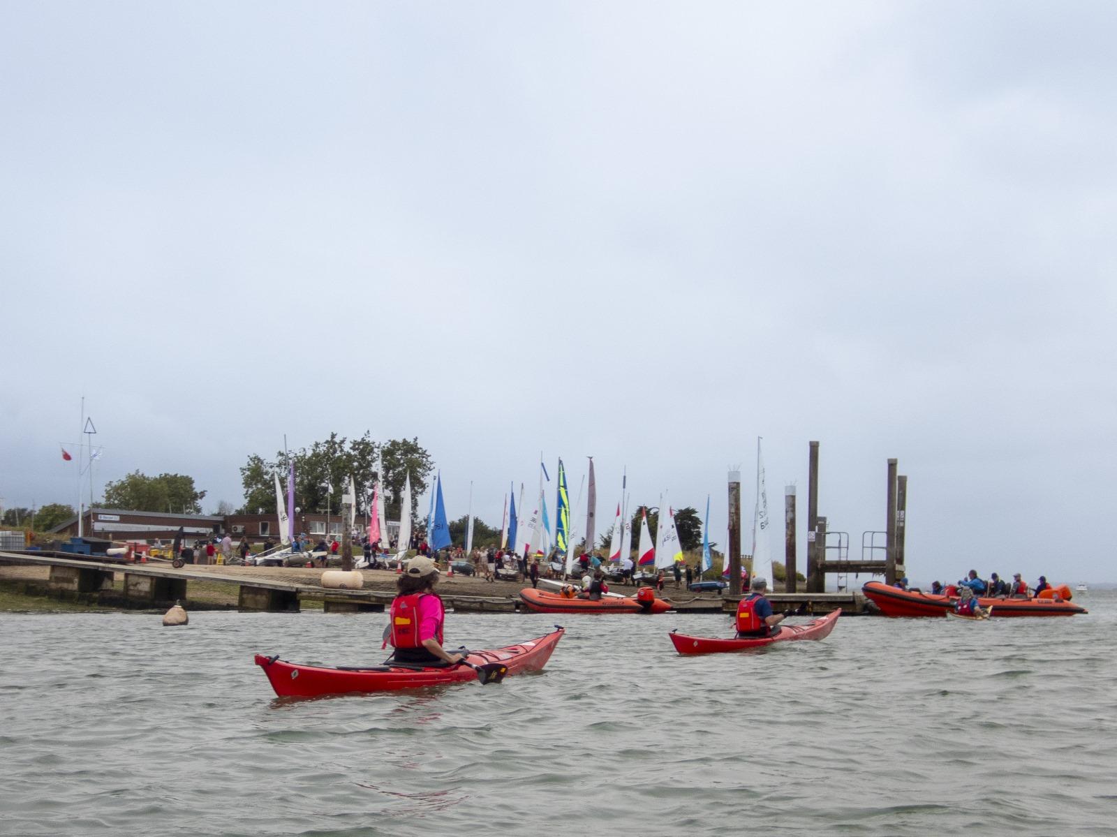 A group of people in kayaks on the water

Description automatically generated