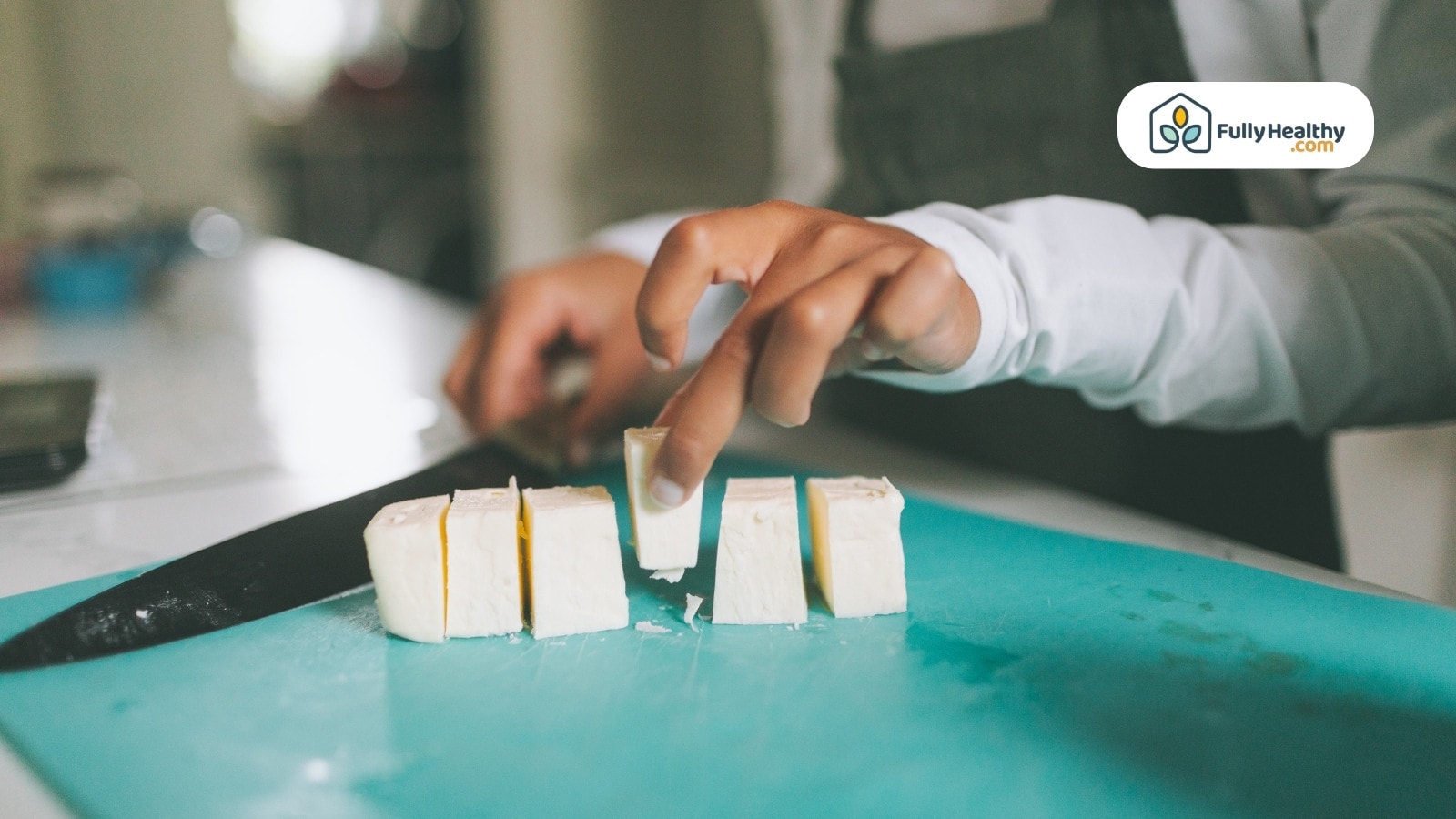 Person slicing butter into cubes on a teal cutting board