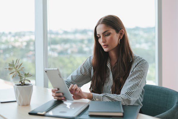 young businesswoman, demonstrating strong administrative skills, sits at her office desk, focused on a digital tablet