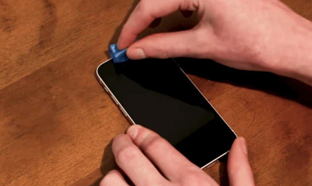 Person cleaning an iPhone using a blue tape