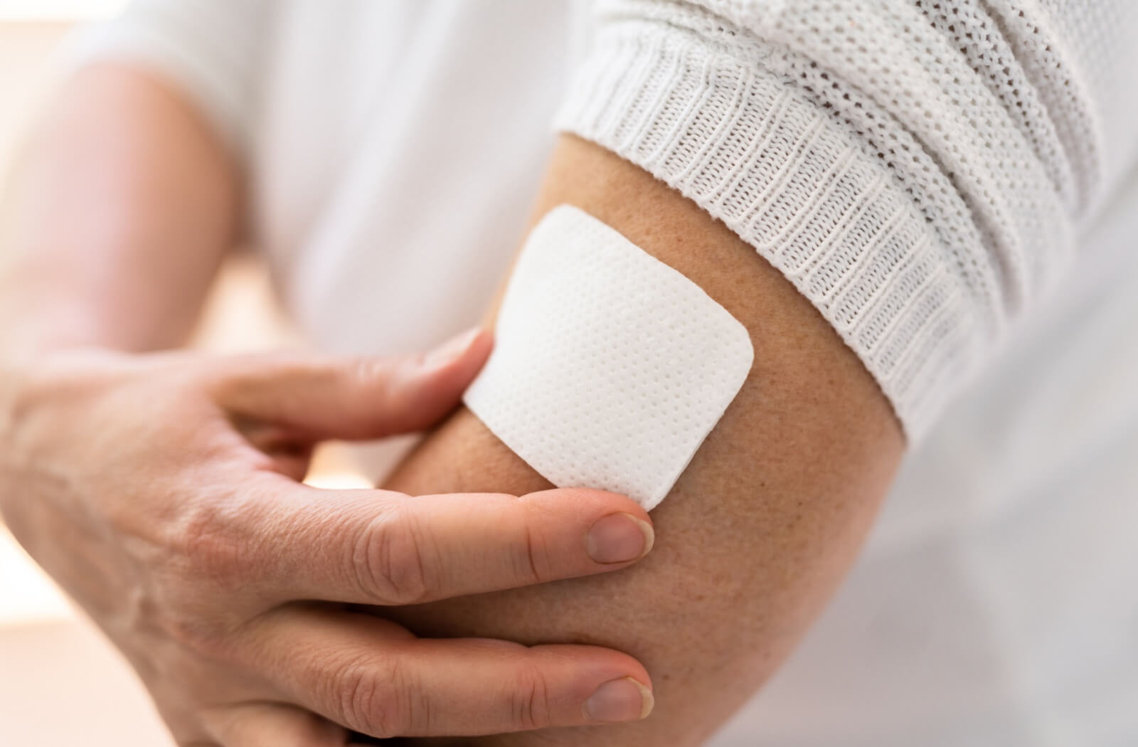 A close up image of an older adult placing a smoking cessation patch on their arm.