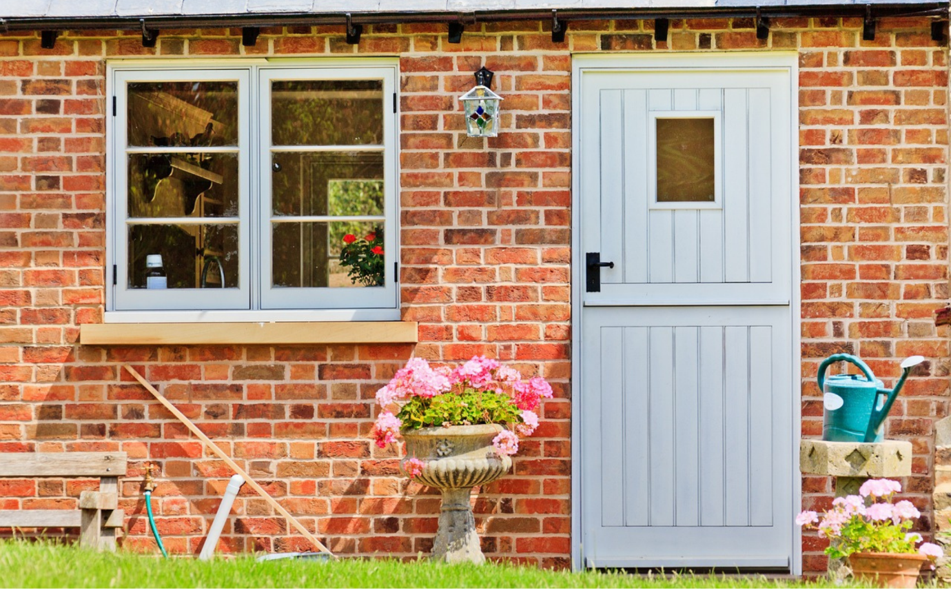 A brick house with a door and a flower potDescription automatically generated