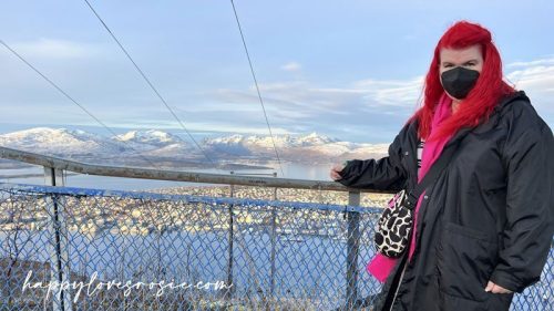 woman standing at the top of the mountain in tromso