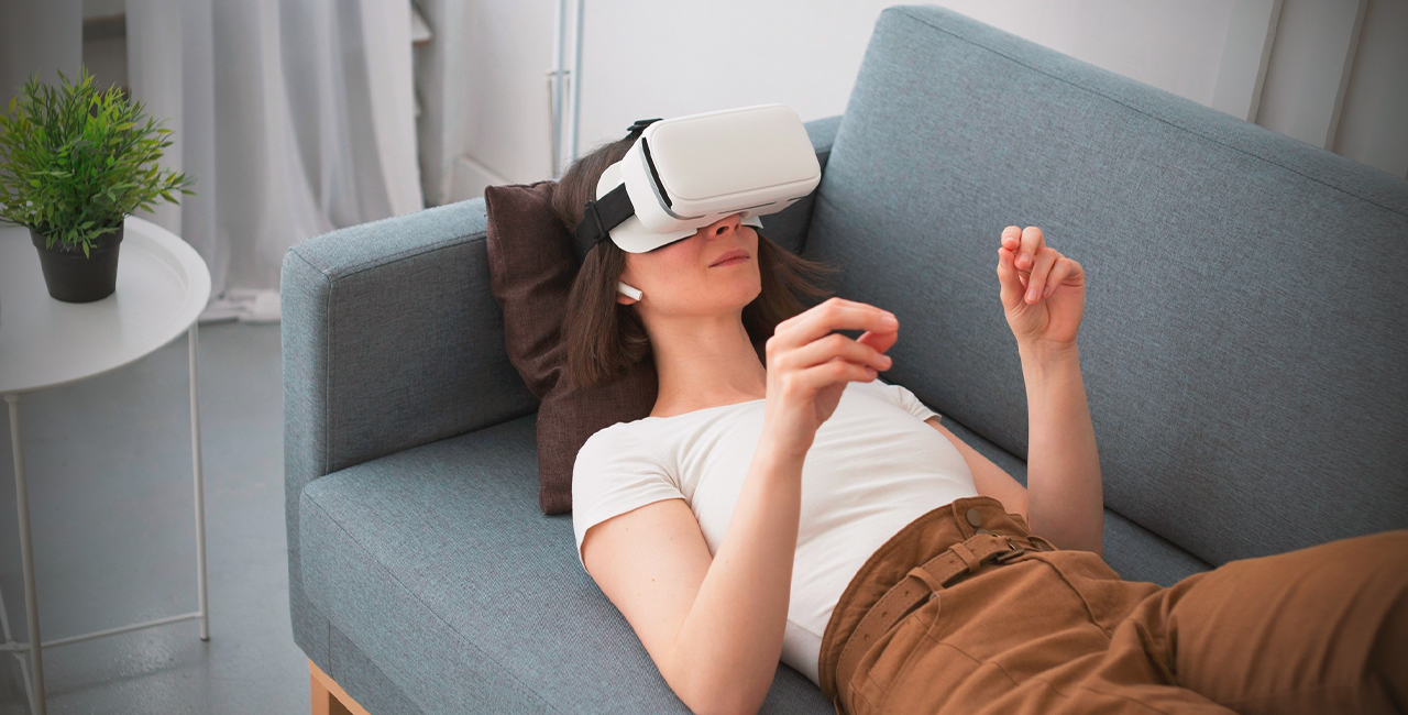 A woman relaxes on a couch, immersed in a virtual reality experience with a headset on