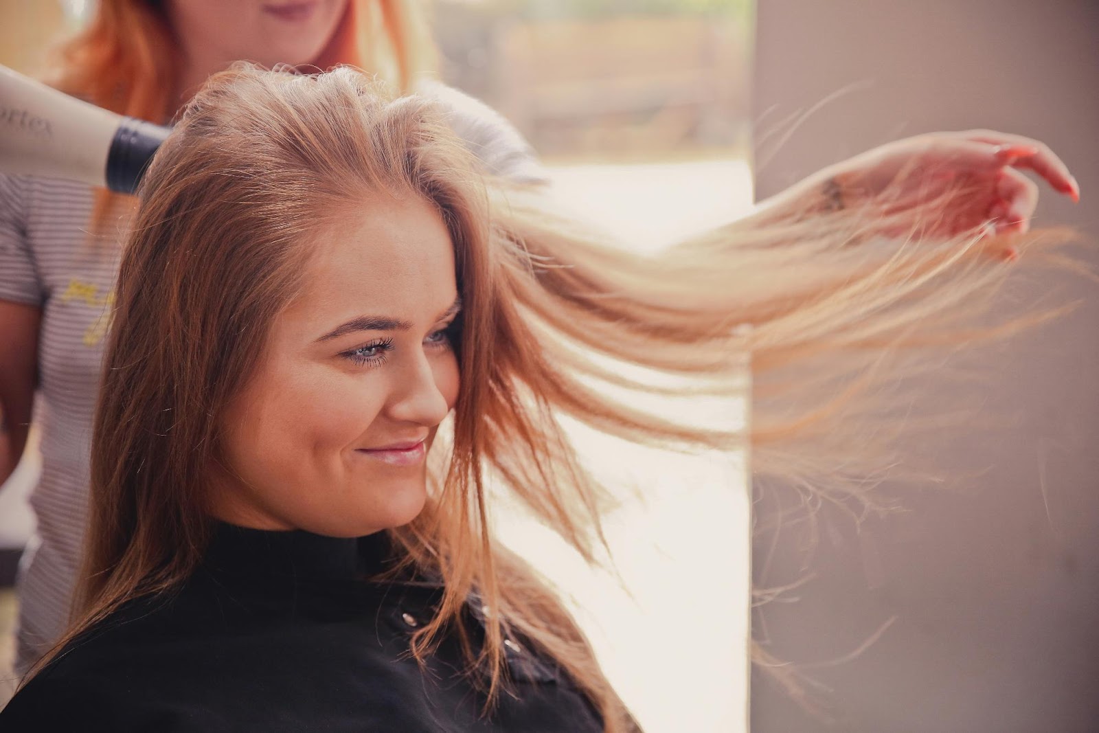 Woman smiling during salon blowout after installing clip-in extensions