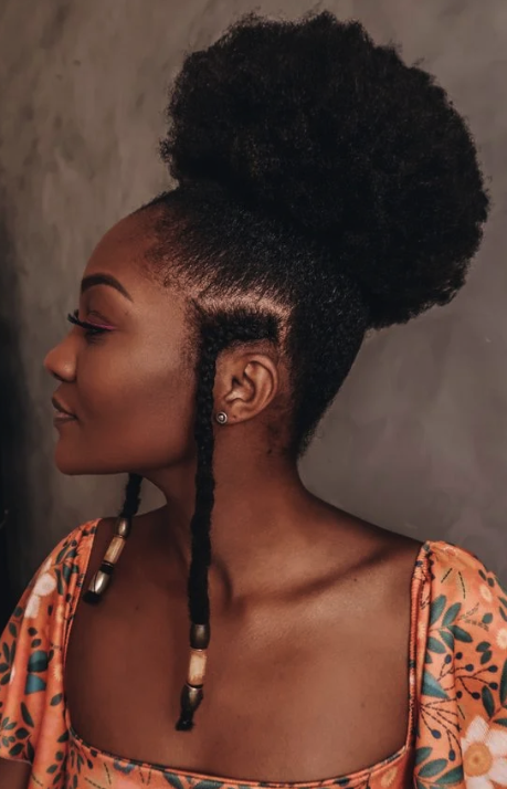 Mulher negra com penteado de coque com duas trancinhas, uma de cada lado