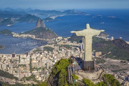 A statue of a person on Christ the Redeemer with a city in the background

Description automatically generated