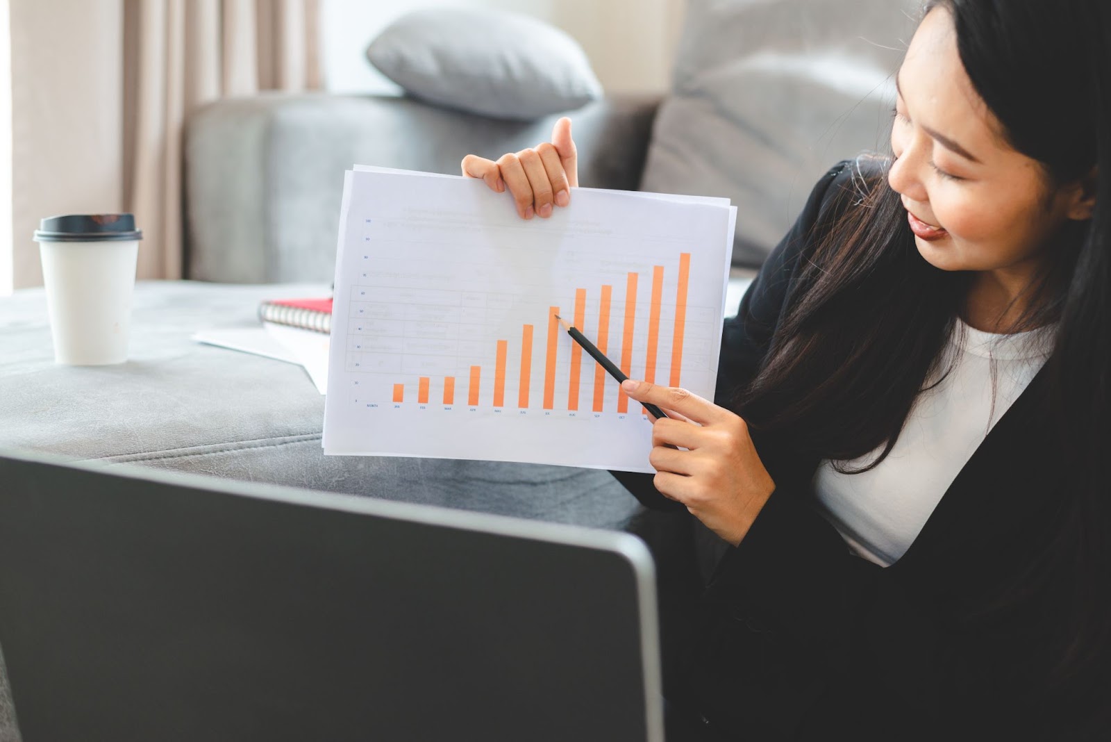 Women holding a piece of paper with a graph on it and pointing at data using a pencil. 