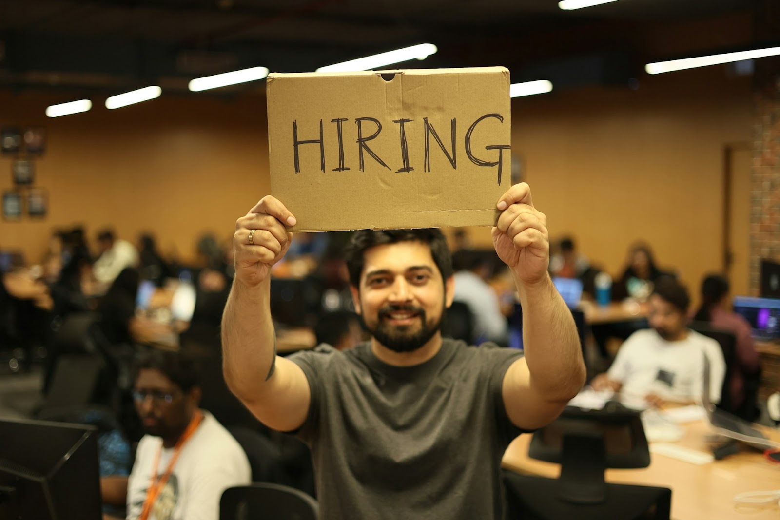 A man holding a sign that says "Hiring"