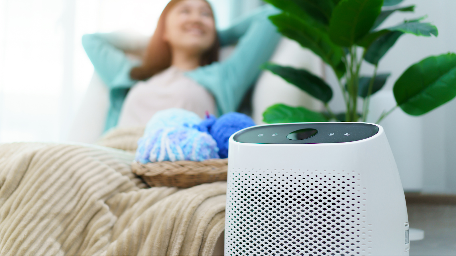 Air purifier dengan perempuan sedang bersantai di belakangnya / Sumber: canva